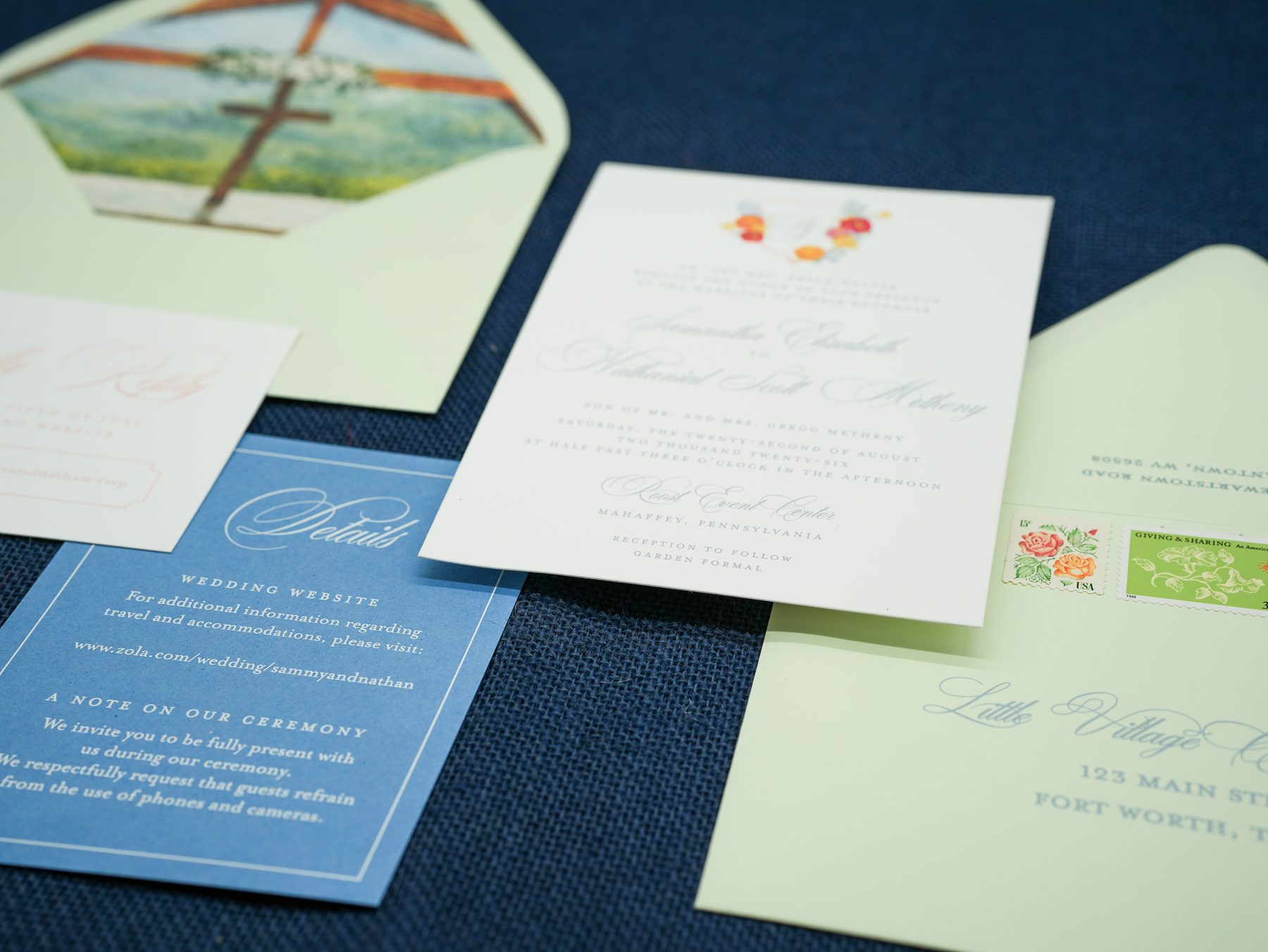 Close-up of a coral floral wedding invitation tucked into its mint envelope with a watercolor chapel liner.