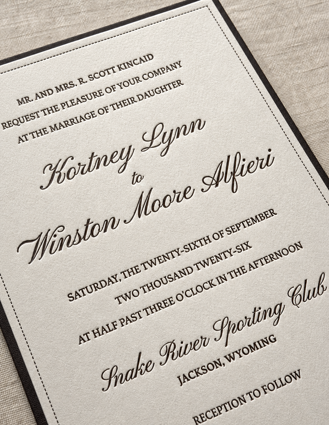 A close-up of a letterpress wedding invitation in cream and ink.