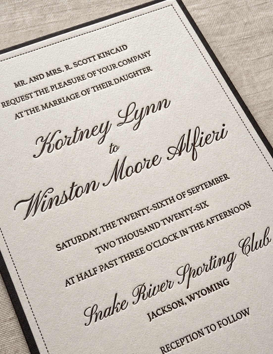 A close-up of a letterpress wedding invitation in cream and ink.