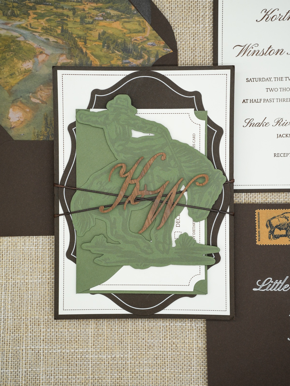 The bronc rider band and monogram framed by the scalloped invitation border.