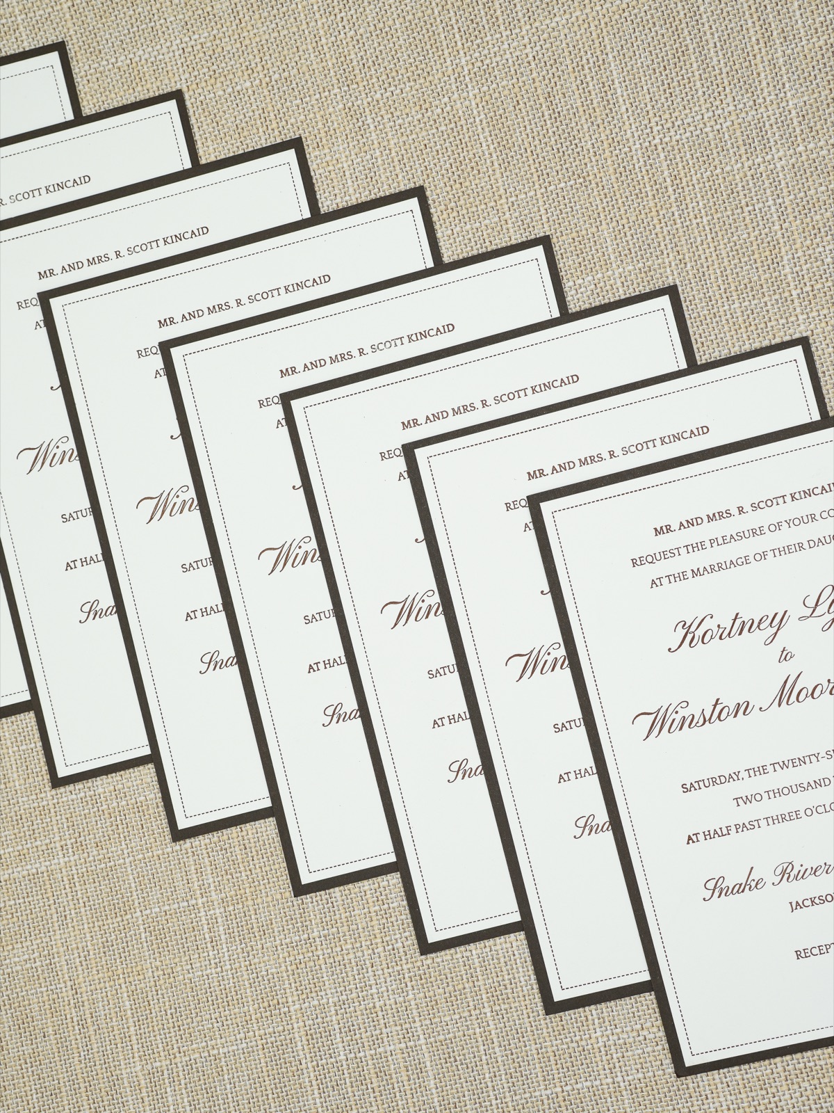 A fanned stack of letterpress invitations edged in chocolate brown.