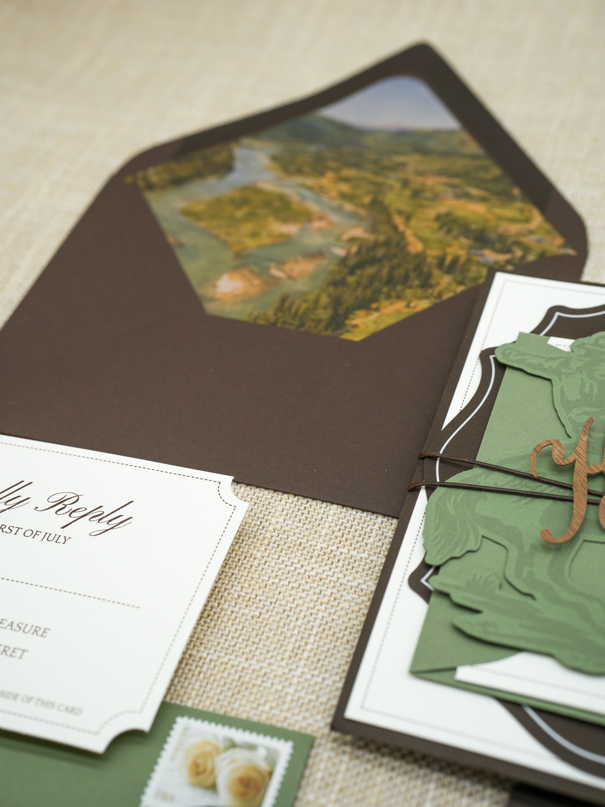The scenic watercolor liner in a brown envelope beside the scalloped reply card.