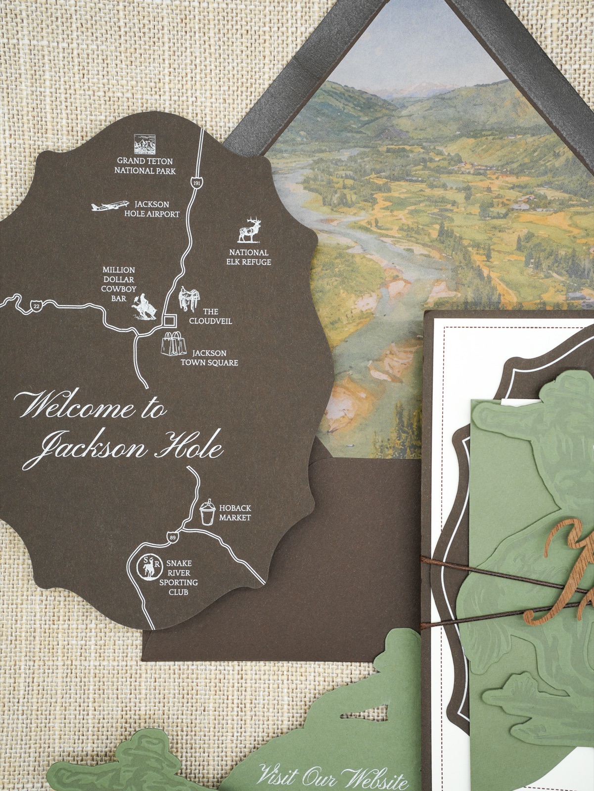 A die-cut welcome card with a hand-drawn map, layered over the watercolor envelope liner.