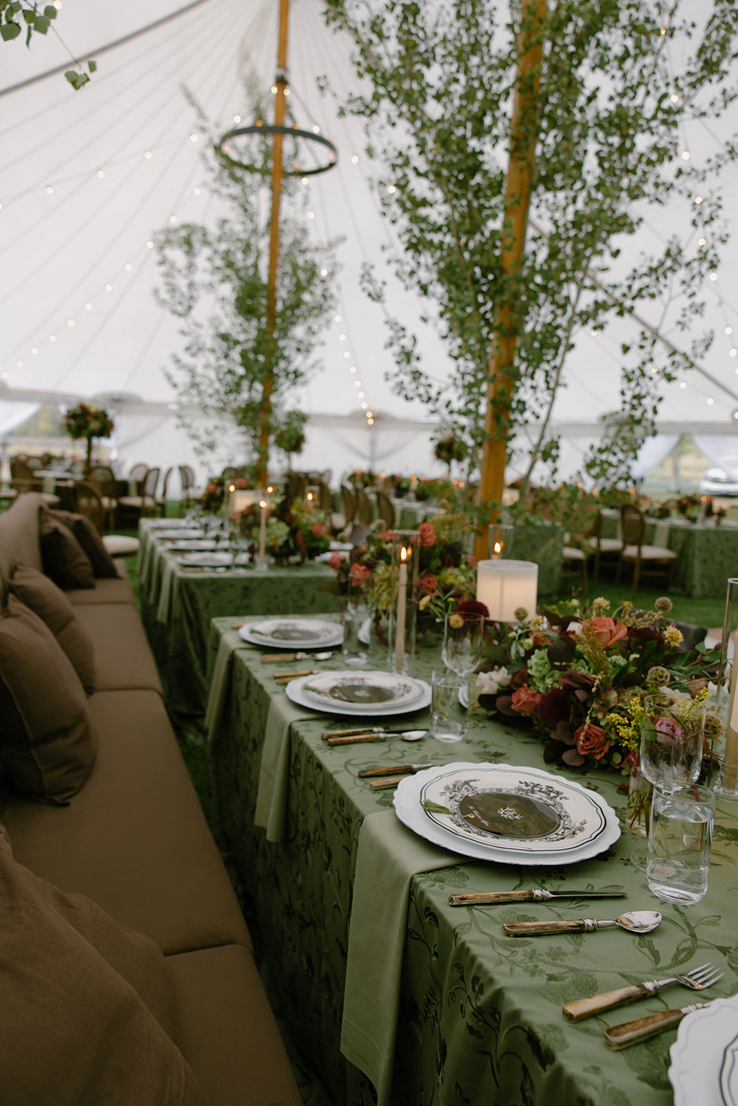 A long reception table under the tent, dressed in sage floral linens.