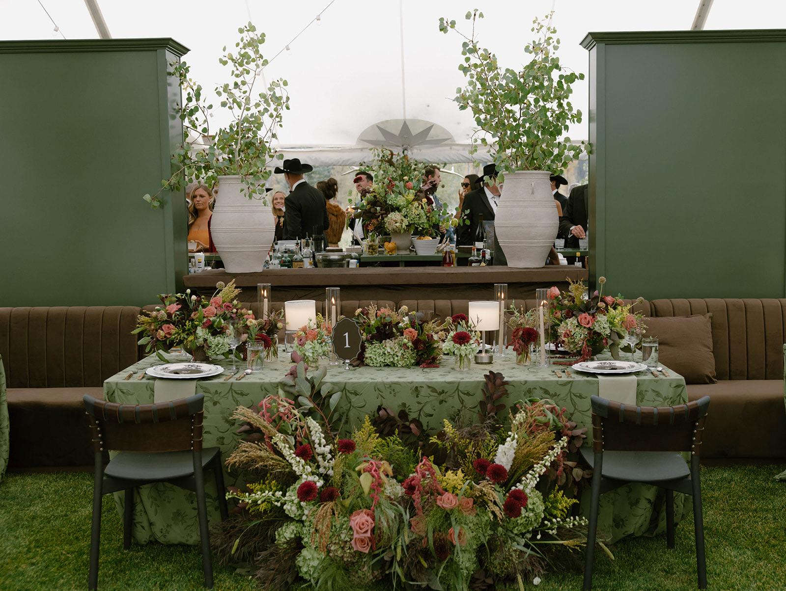 The tented reception with the head table framed by stone urns of greenery.