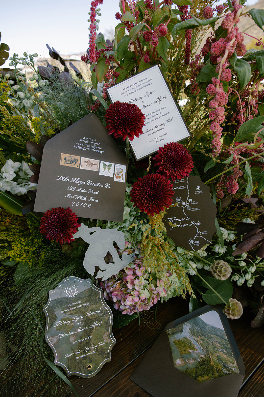 The suite's die-cut cards arranged among deep red dahlias and trailing blooms.