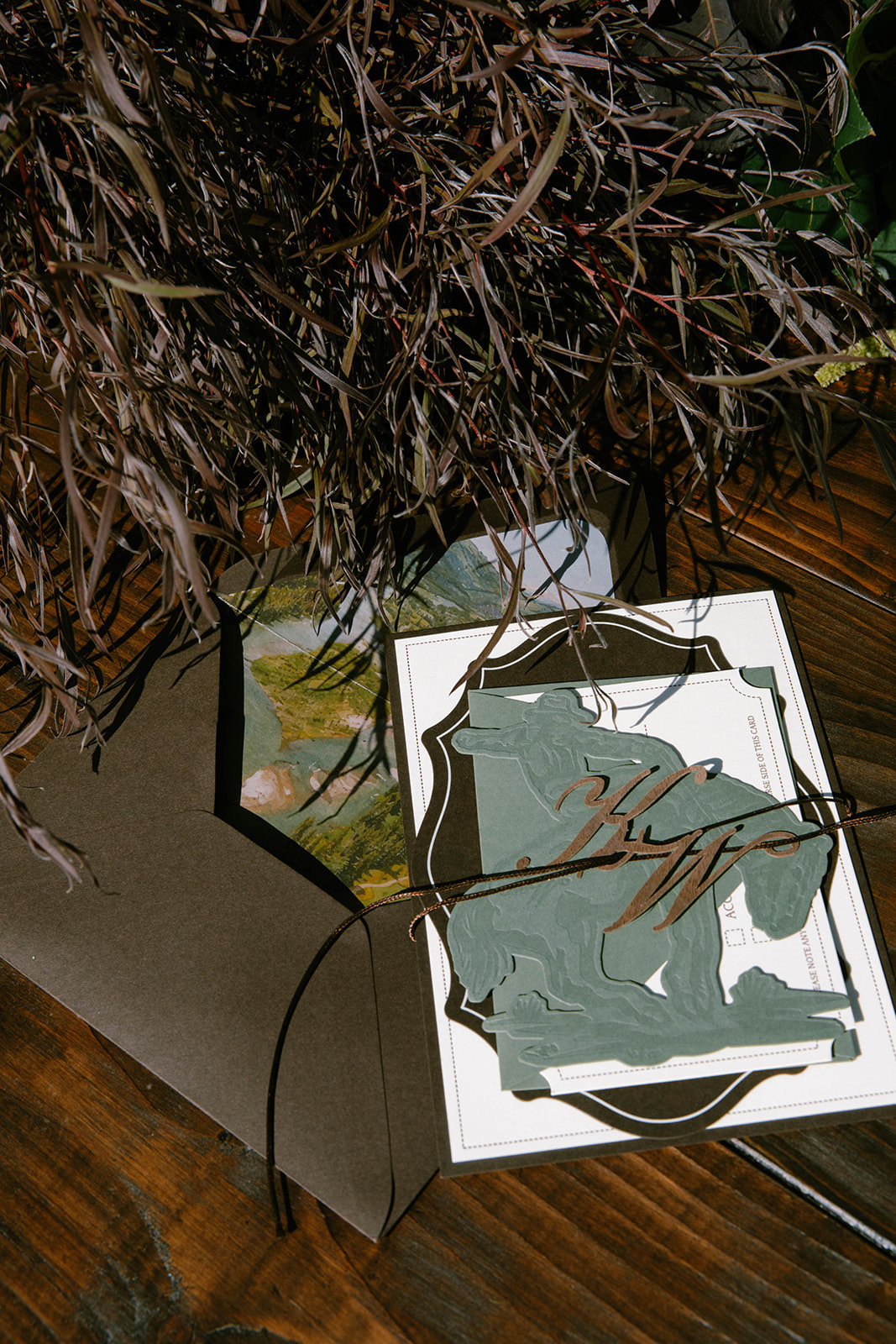 A vellum detail card with a landscape print layered over dried grasses.
