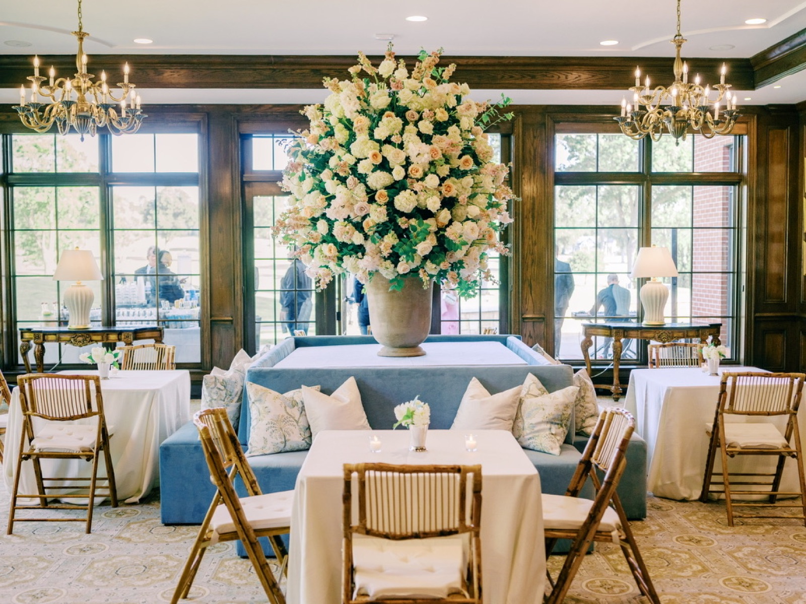The cocktail room: a blue velvet sofa, bamboo chairs, and a towering peach arrangement.