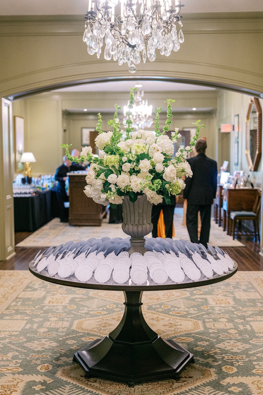 The club foyer: escort cards fanned around an urn of white flowers beneath a chandelier.