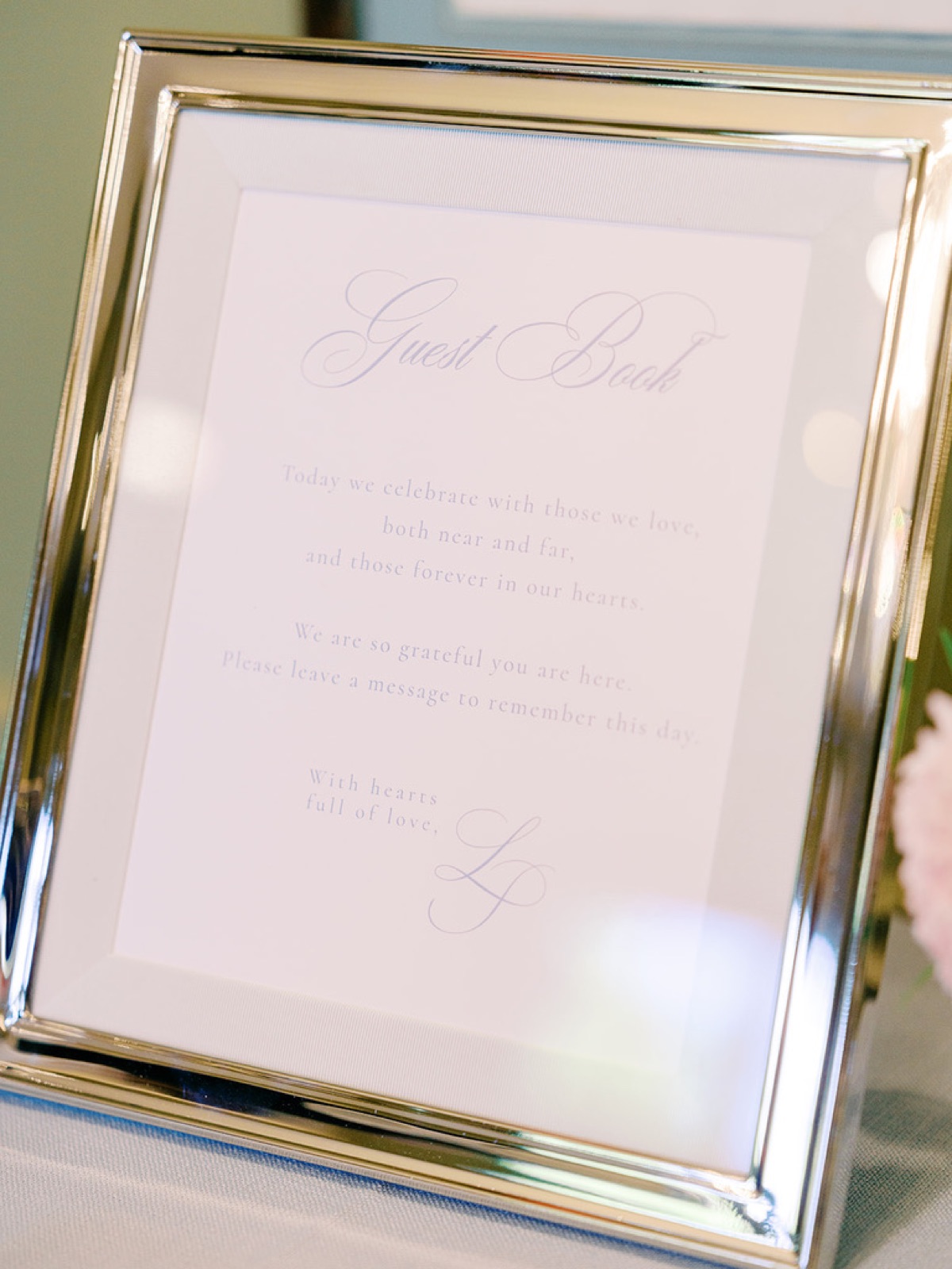A silver-framed guest book sign lettered in soft blue.