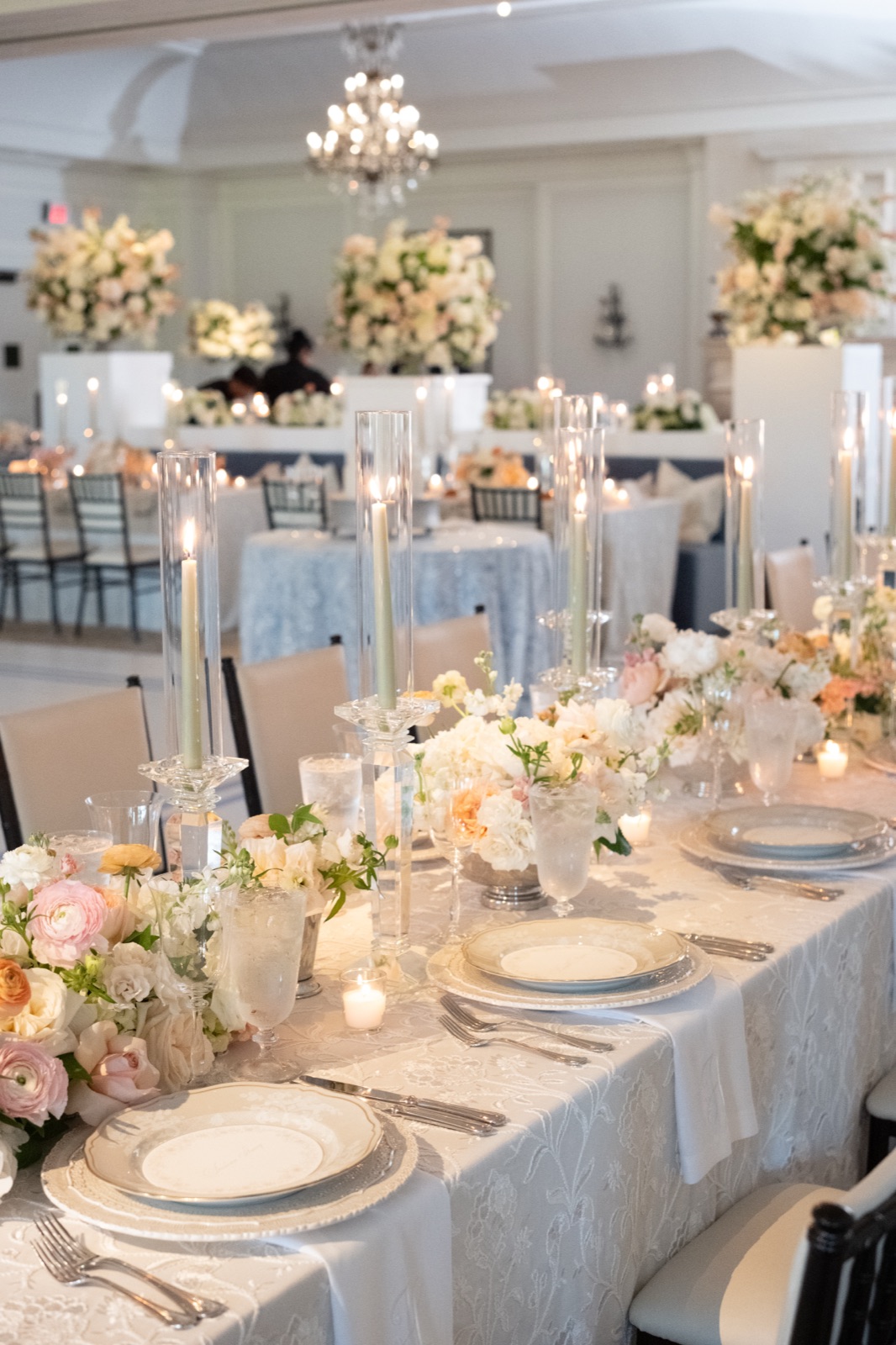 The reception room in full: lace linens, crystal candlesticks, and arrangements in white and peach.