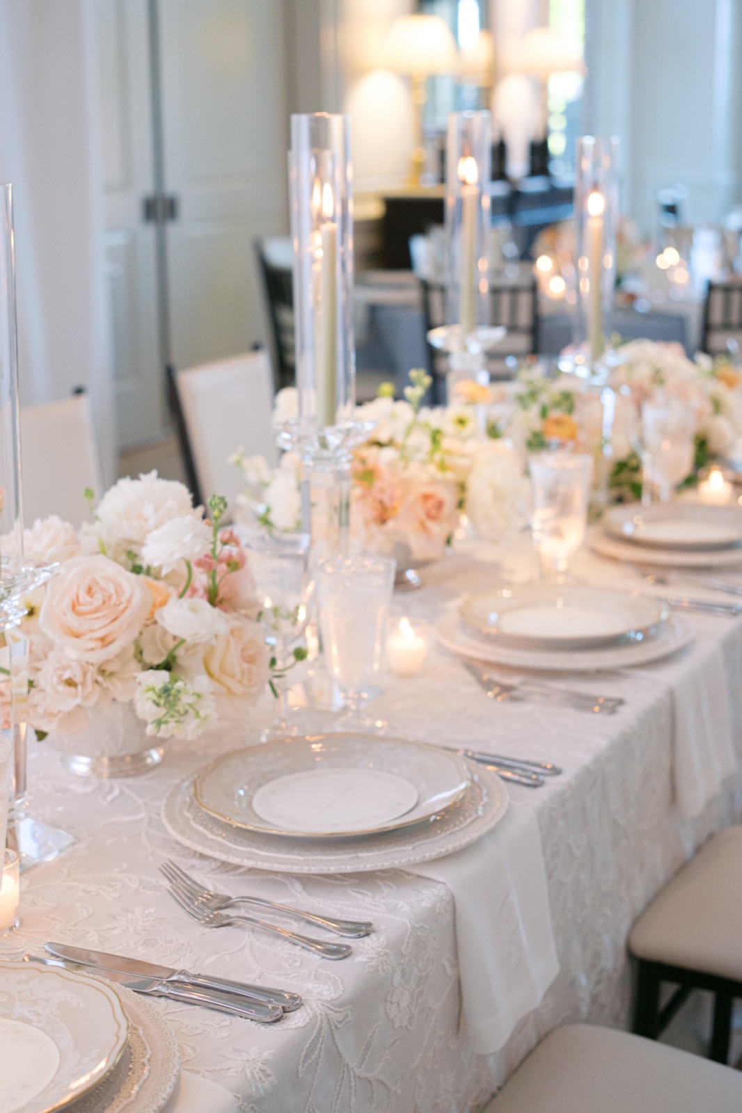Reception tables layered with lace linens, crystal candlesticks, and blush arrangements.