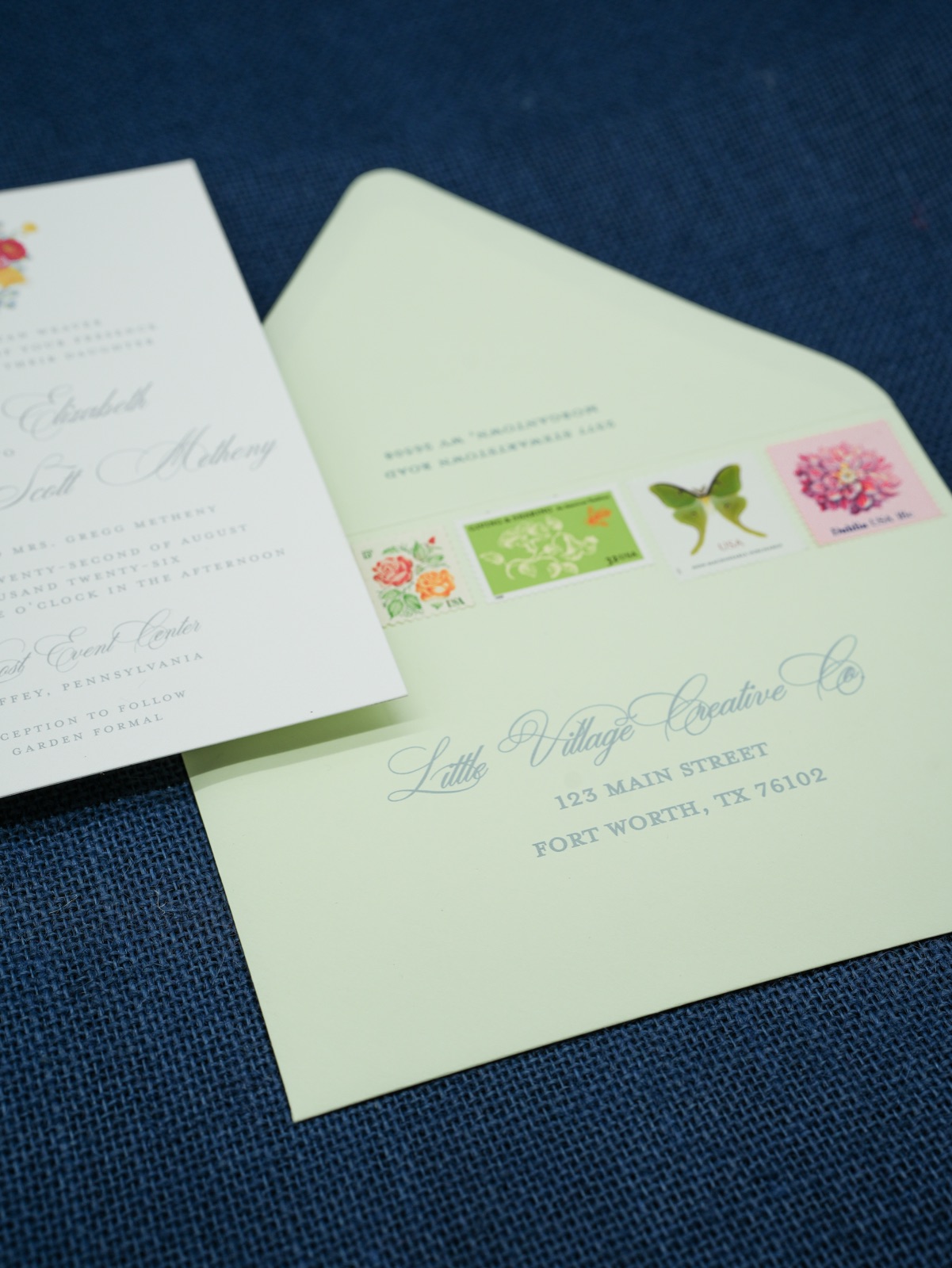 A soft green envelope addressed in sage calligraphy with garden vintage stamps.