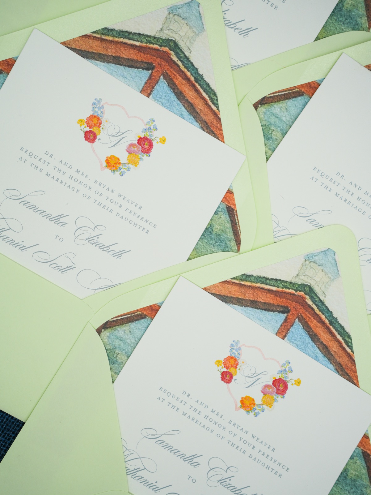 Invitations layered over soft green chapel-lined envelopes.