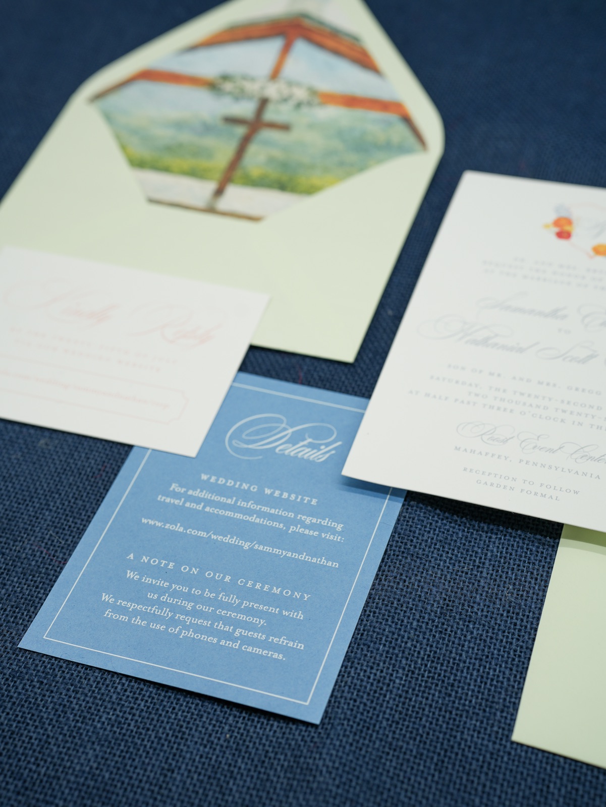 The watercolor chapel envelope liner behind the blush reply card and French blue details card.