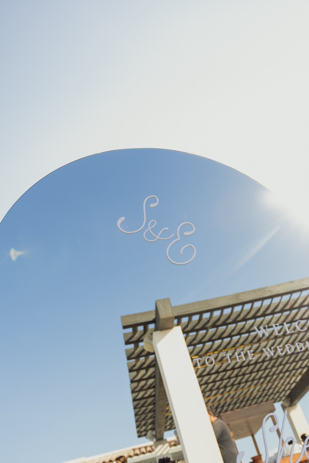 The couple's monogram lettered on an arch sign against the sky.