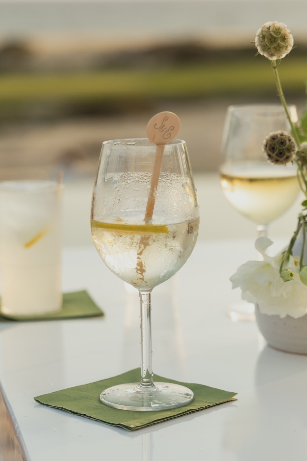 A monogrammed stirrer in a spritz on a sage cocktail napkin.