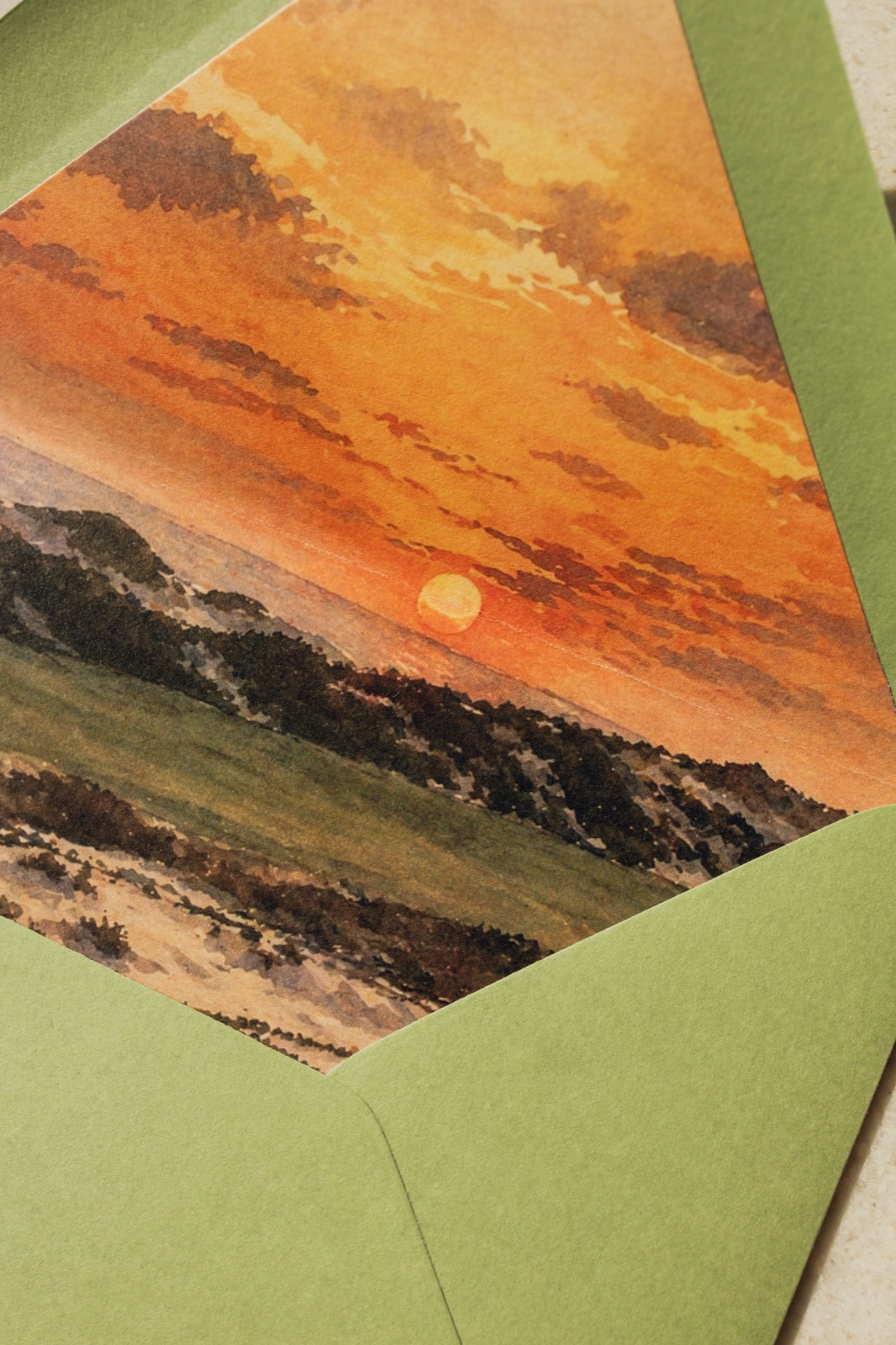 A hand-painted sunset envelope liner in a moss green envelope.
