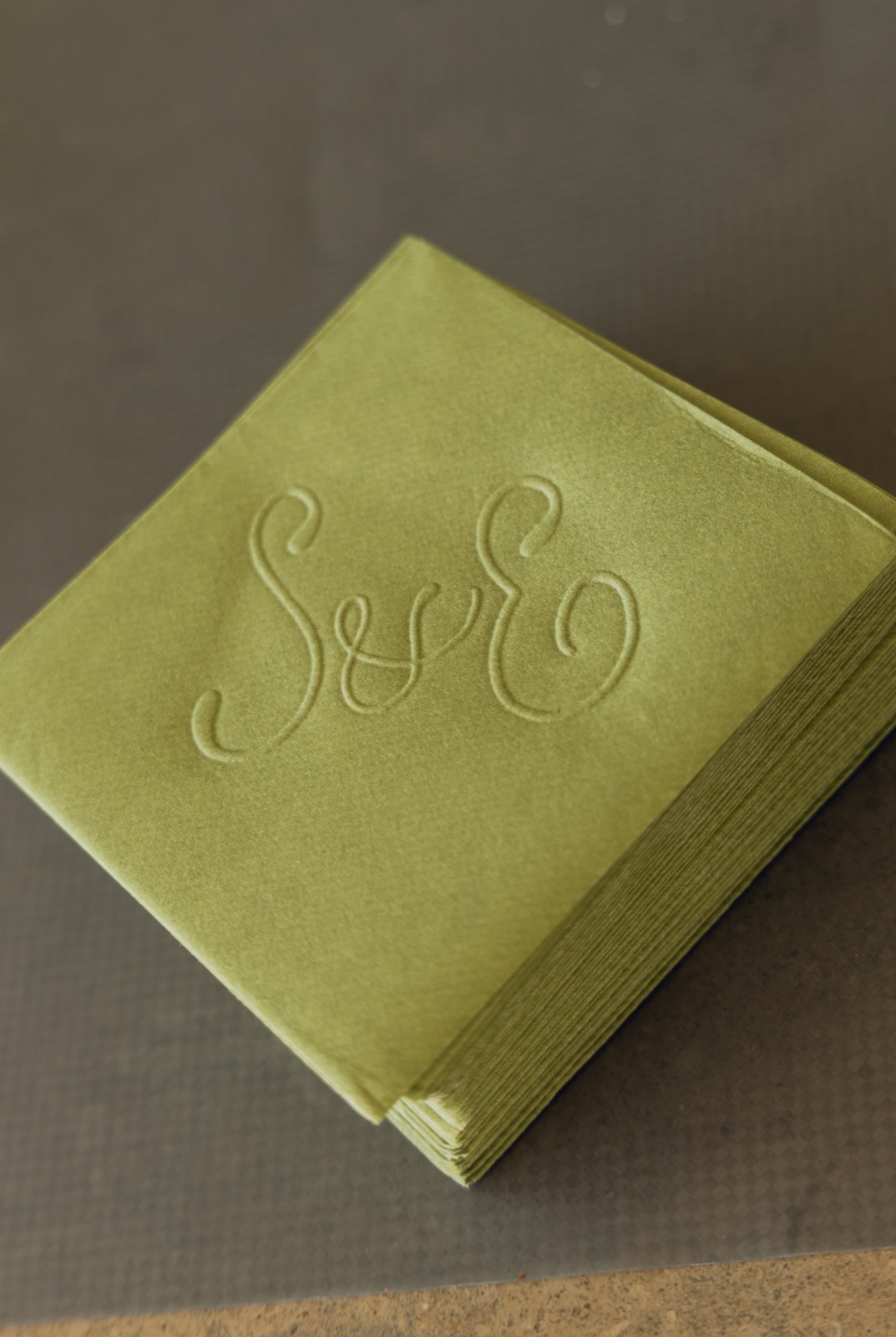Sage cocktail napkins embossed with the couple's monogram.