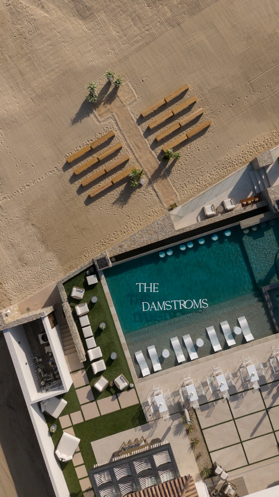 The pool deck lettered for the couple from above, framed by cabanas.