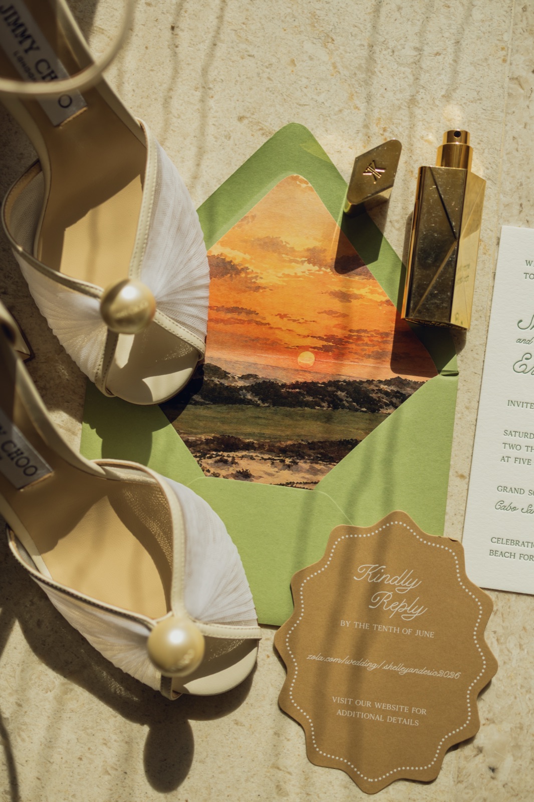 The invitation styled with a sunset envelope liner, kraft details tag, and pearl heels.