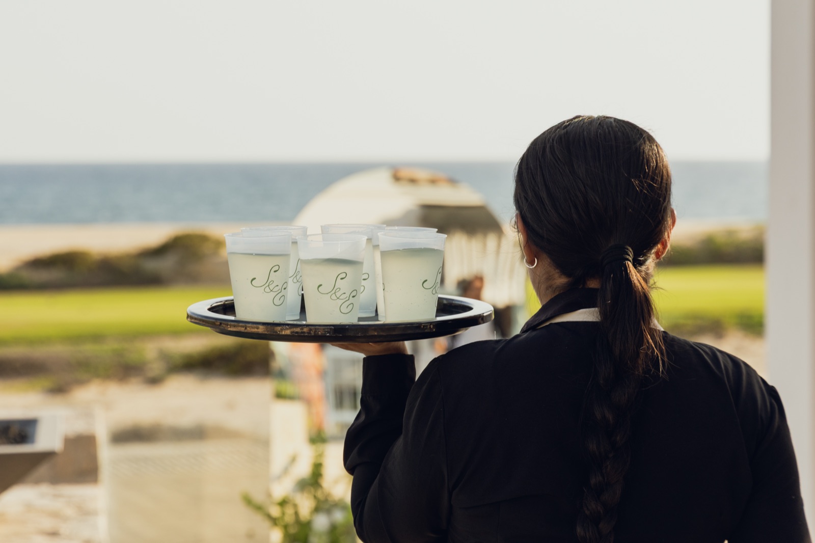Monogrammed cups served on a tray by the sea.