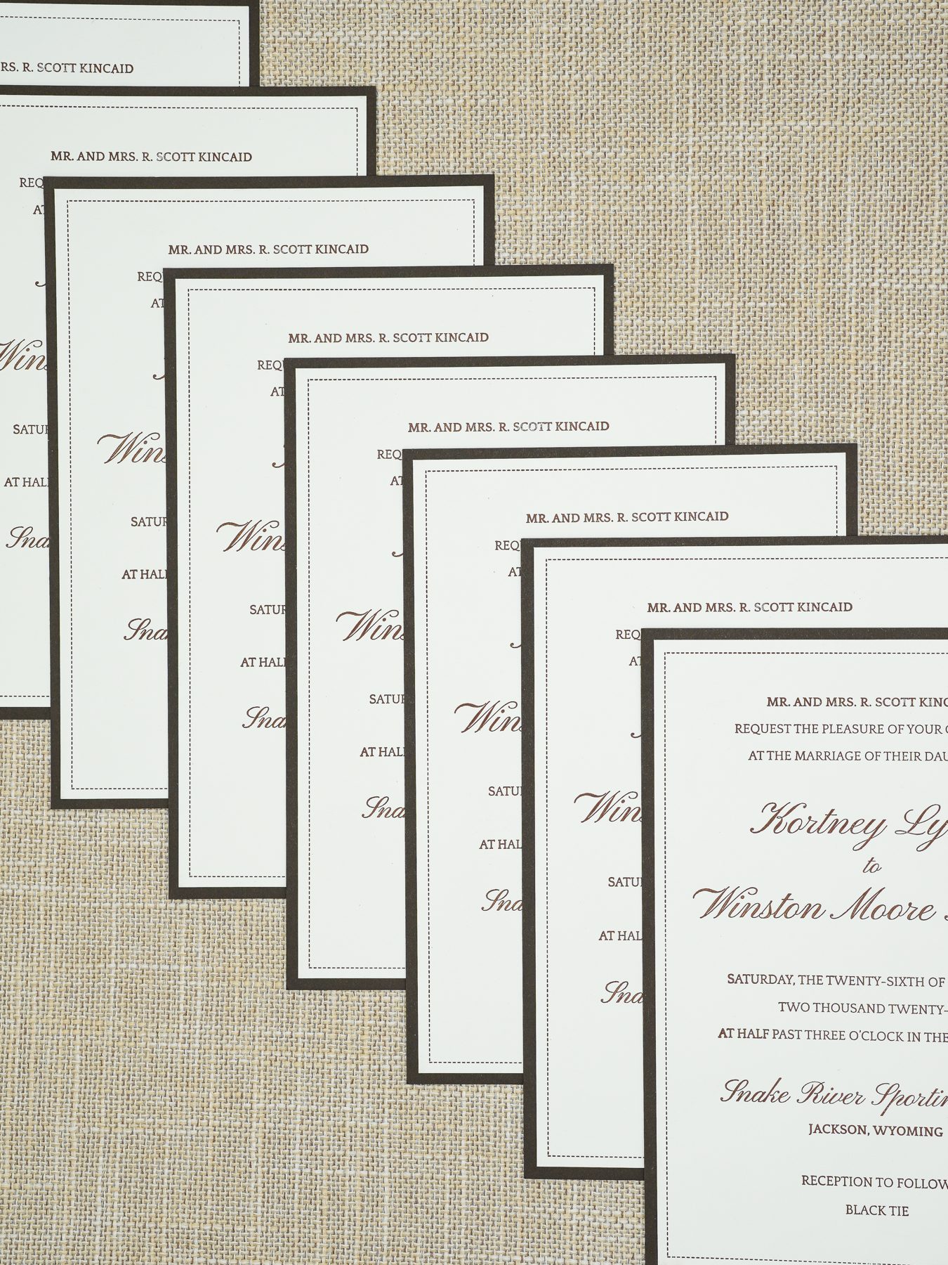 A fan of die-cut hunter-green wedding cards with watercolor cowboy and horse silhouettes.