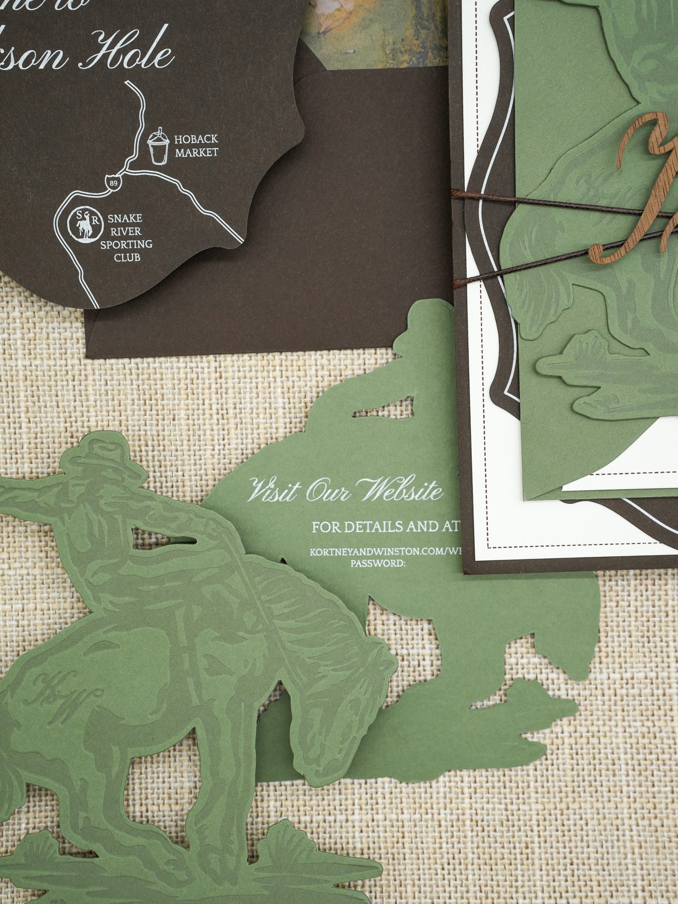 A sage-green die-cut horse silhouette resting over a custom watercolor wedding map.